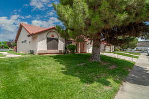 Mediterranean / spanish home with a tiled roof, stucco siding, a front lawn, concrete driveway, and an attached garage