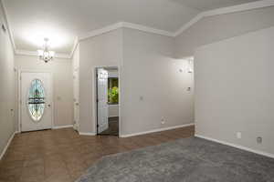 Foyer entrance featuring a chandelier, healthy amount of natural light, lofted ceiling, and baseboards