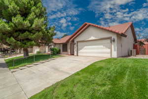 View of front of house featuring a garage, a front yard, a tiled roof, and concrete driveway