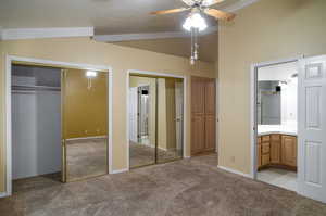 Unfurnished bedroom with two closets, vaulted ceiling, carpet floors, and ensuite bathroom