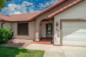 Property entrance with stucco siding, a tiled roof, and an attached garage