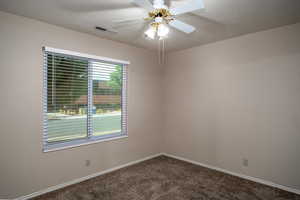 Empty room featuring dark colored carpet, ceiling fan, a textured ceiling, and baseboards