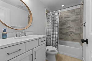 Bathroom with vanity, shower / bath combo, and wood finish floors
