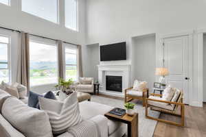 Living area with a high ceiling, a glass covered fireplace, and light wood finished floors