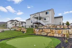 Back of house featuring a putting area, stairs, a yard, and a deck