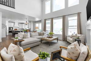 Living area featuring a towering ceiling, light wood-style floors, recessed lighting, and plenty of natural light