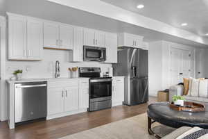 Kitchen featuring stainless steel appliances, light countertops, dark wood-style flooring, white cabinetry, and recessed lighting