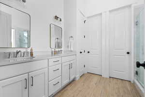 Full bath with double vanity, a stall shower, and wood tiled floors