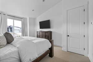 Bedroom featuring vaulted ceiling, carpet flooring, and access to outside
