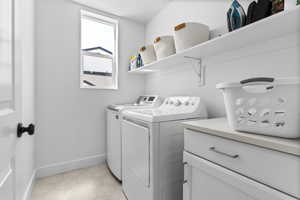 Laundry room with independent washer and dryer and light tile patterned floors