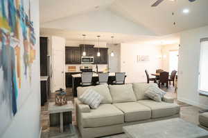 Living room featuring lofted ceiling, a ceiling fan, recessed lighting, and a chandelier