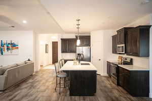 Kitchen featuring appliances with stainless steel finishes, open floor plan, backsplash, dark wood-style floors, and light countertops