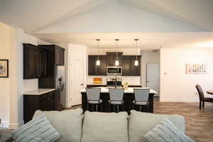 Living room with lofted ceiling, dark wood-style floors, and recessed lighting