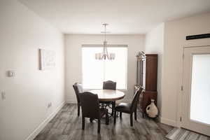 Dining space with a chandelier and dark wood-type flooring