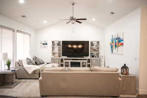 Living room with a ceiling fan, lofted ceiling, recessed lighting, and a glass covered fireplace