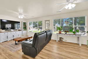 Living room with ceiling fan and light wood-type flooring