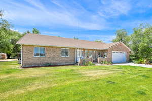 Single story home with concrete driveway, brick siding, a front lawn, an attached garage, and a shingled roof