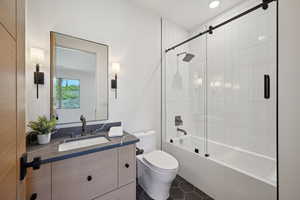 Full bath featuring toilet, vanity, bath / shower combo with glass door, and tile patterned flooring