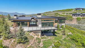 Rear view of house with a standing seam roof, metal roof, a chimney, stone siding, and a mountain view