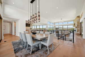 Dining space with a chandelier, light wood-style flooring, a towering ceiling, recessed lighting, and baseboards