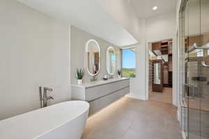 Bathroom with double vanity, a freestanding tub, a shower stall, baseboards, and recessed lighting