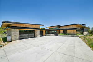 Contemporary house with stone siding, driveway, and a garage