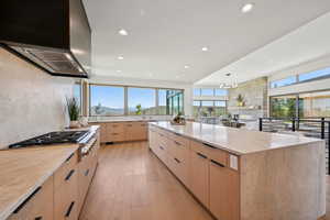 Kitchen featuring light brown cabinets, modern cabinets, wall chimney range hood, recessed lighting, and light wood-type flooring