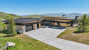 View of front of house featuring a standing seam roof, stone siding, a mountain view, and a chimney