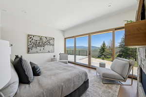 Bedroom featuring a mountain view, access to exterior, wood finished floors, and a fireplace