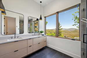 Bathroom with a mountain view, double vanity, baseboards, tile patterned floors, and a shower with shower door