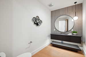 Bathroom with toilet, wood finished floors, vanity, and baseboards