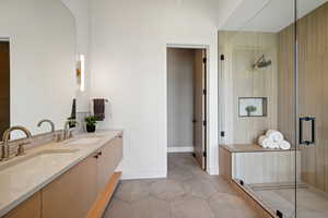 Full bath with a stall shower, double vanity, tile patterned flooring, and baseboards