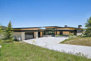 Contemporary house featuring concrete driveway, stone siding, and an attached garage