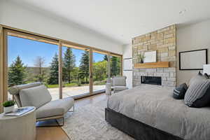 Bedroom with access to outside, wood finished floors, and a fireplace