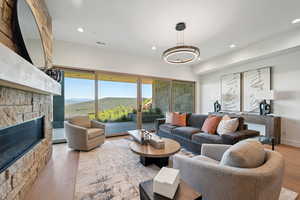 Living area featuring wood finished floors, recessed lighting, a stone fireplace, and a mountain view