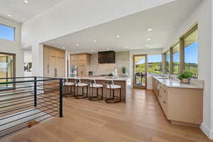 Kitchen featuring light brown cabinetry, a kitchen breakfast bar, light countertops, decorative backsplash, and modern cabinets