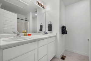 Full bathroom with marble look tiles, double vanity, and a shower