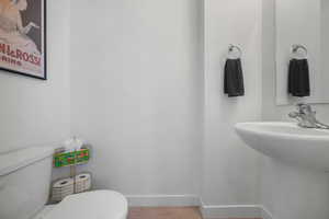 Half bath with toilet and wood finished floors