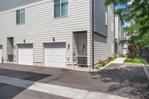 View of side of property featuring a central air condition unit and an attached garage