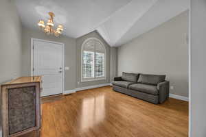 Foyer featuring a chandelier, wood finished floors, and vaulted ceiling