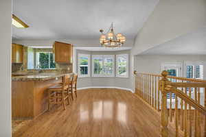 Kitchen with light wood-type flooring, plenty of natural light, brown cabinets, and a chandelier