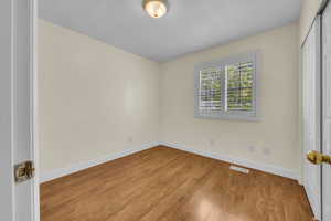 Unfurnished room with wood finished floors and baseboards