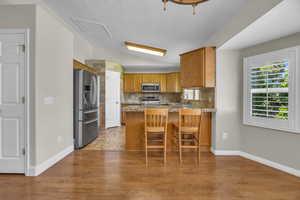 Kitchen featuring stainless steel appliances, a peninsula, lofted ceiling, decorative backsplash, and a breakfast bar area