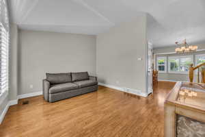 Living area with a chandelier, wood finished floors, and lofted ceiling