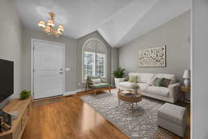 Living room with a chandelier, wood finished floors, and lofted ceiling