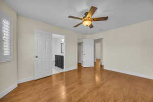 Unfurnished bedroom with light wood-style floors, connected bathroom, and ceiling fan
