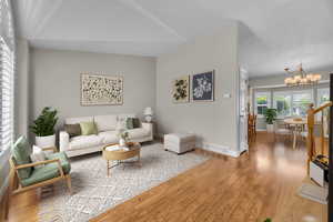 Living area featuring a chandelier, light wood-type flooring, and vaulted ceiling