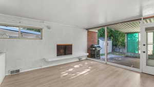 Unfurnished living room with wood finished floors, a fireplace, and healthy amount of natural light