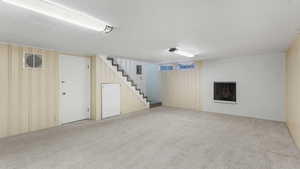 Finished below grade area with carpet floors, stairway, and a brick fireplace