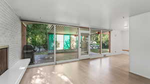Unfurnished room featuring healthy amount of natural light, wood finished floors, brick wall, baseboards, and a fireplace